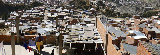 Photo of the dense housing in La Paz. A woman on her rooftop hangs laundry on a line to dry.
