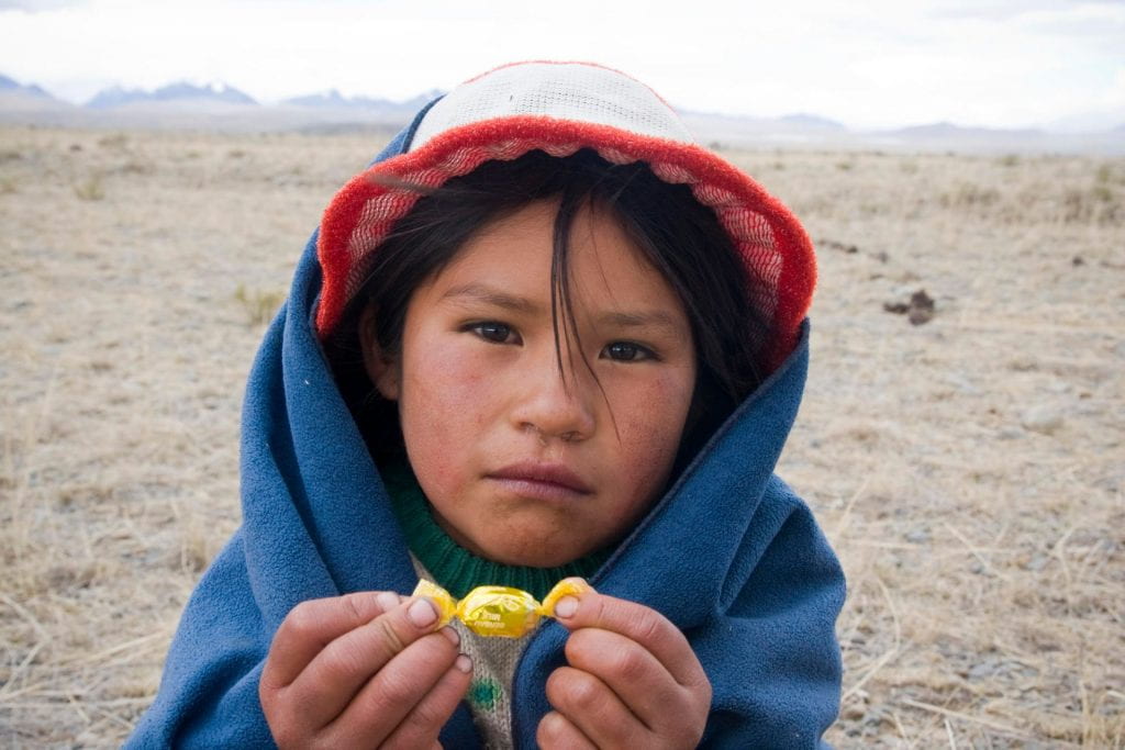 An indigenous child holding a prized piece of candy.