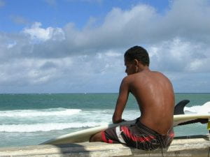 A young man with a surfboard gazes out at the water in Salvdor da Bahia, in northeastern Brazil.