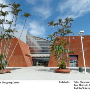 Photo of exterior of the Galerias Miraflores Shopping Center, a modern brick building with sides slanted like a pyramid, and a high glass entryway.