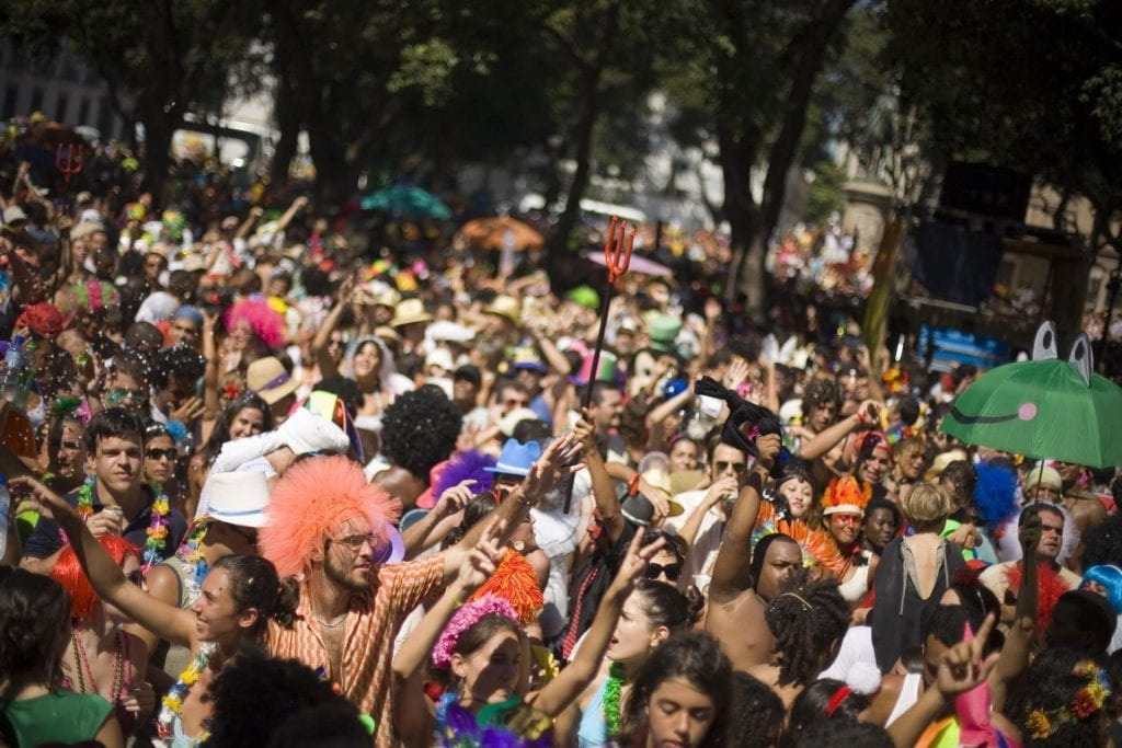 A crowded street in Rio de Janeiro for the Carnaval. People are wearing colorful necklaces and wigs.