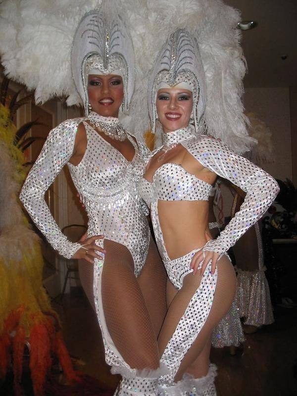 Two Brazilian passista dancers pose in their beaded thong and exaggerated headpiece. The article's author is on the right.