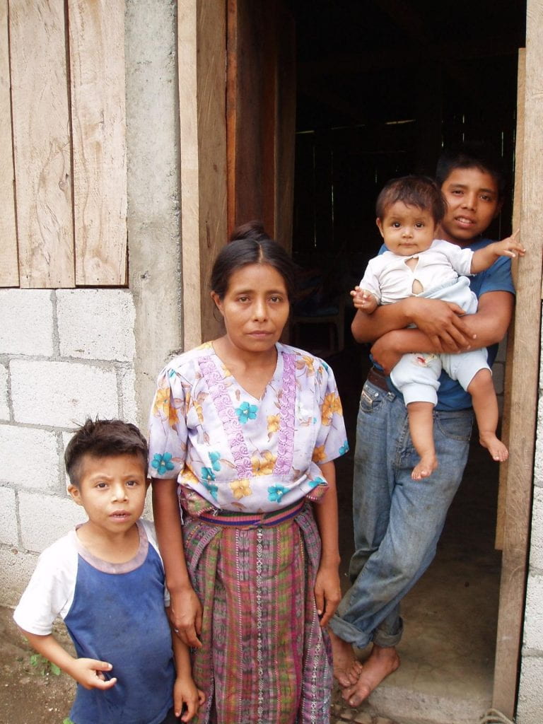 A local family (mother and three children) poses in their doorway