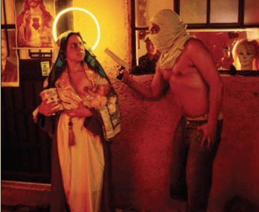 Photographer Nelson Garrido combines the sacred in profane in his photography. Here, the image depicts The Virgibn, with a neon halo heind her head and one breast exposed, being robbed by a man in a hood with a gun. Behind her to the left, there is a picture of Jesus.